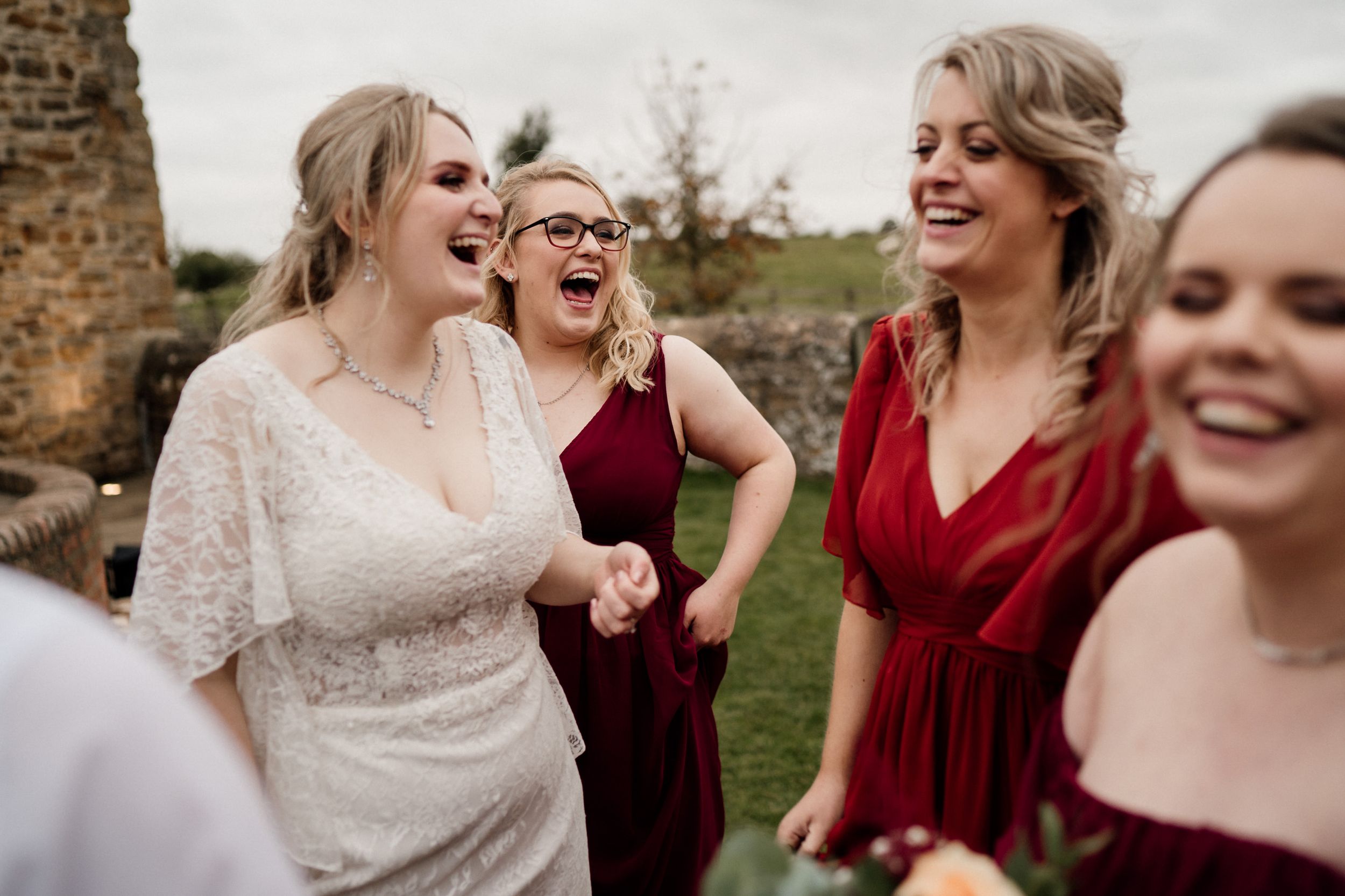 A joyful candid moment at a wedding celebration with laughter and burgundy dresses.