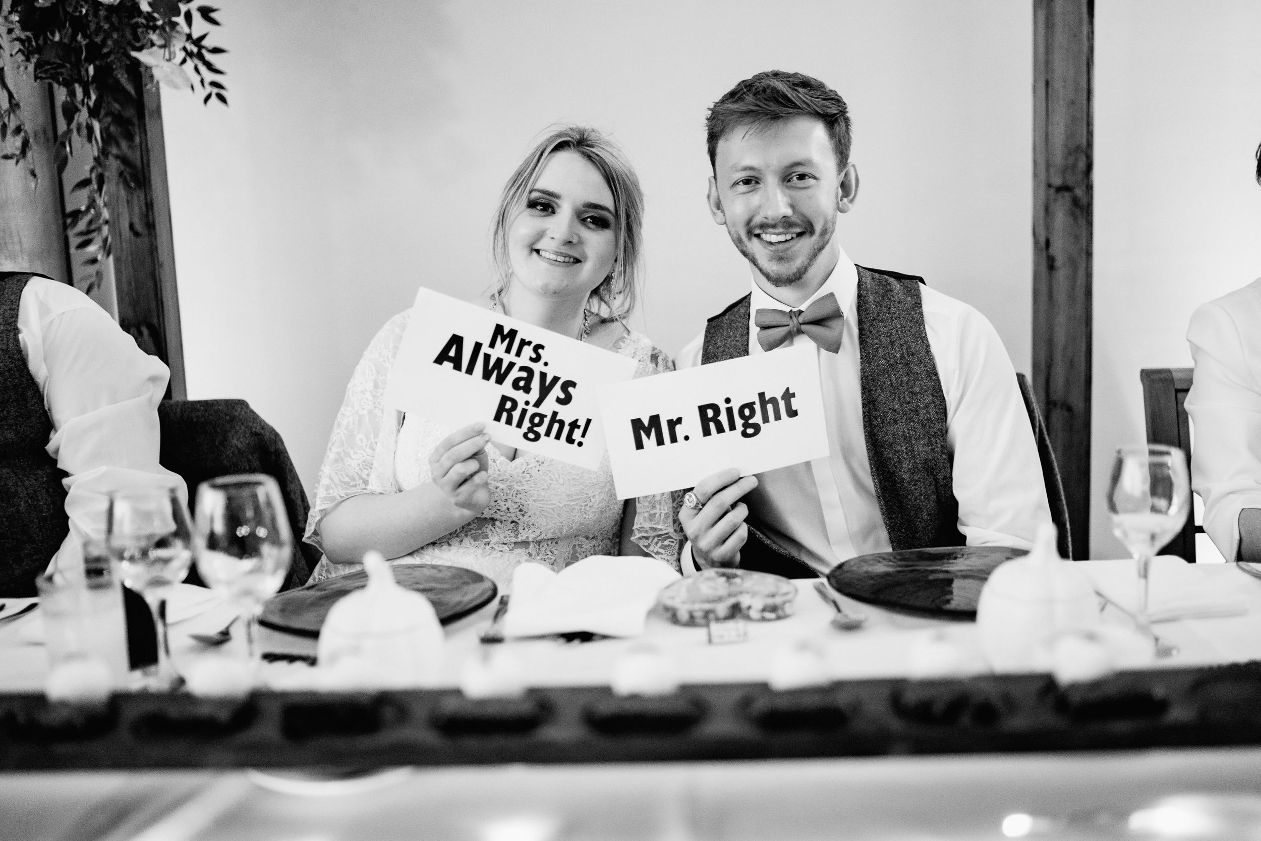 Newlyweds share a lighthearted moment at their reception table wearing matching Mr. and Mrs. shirts.