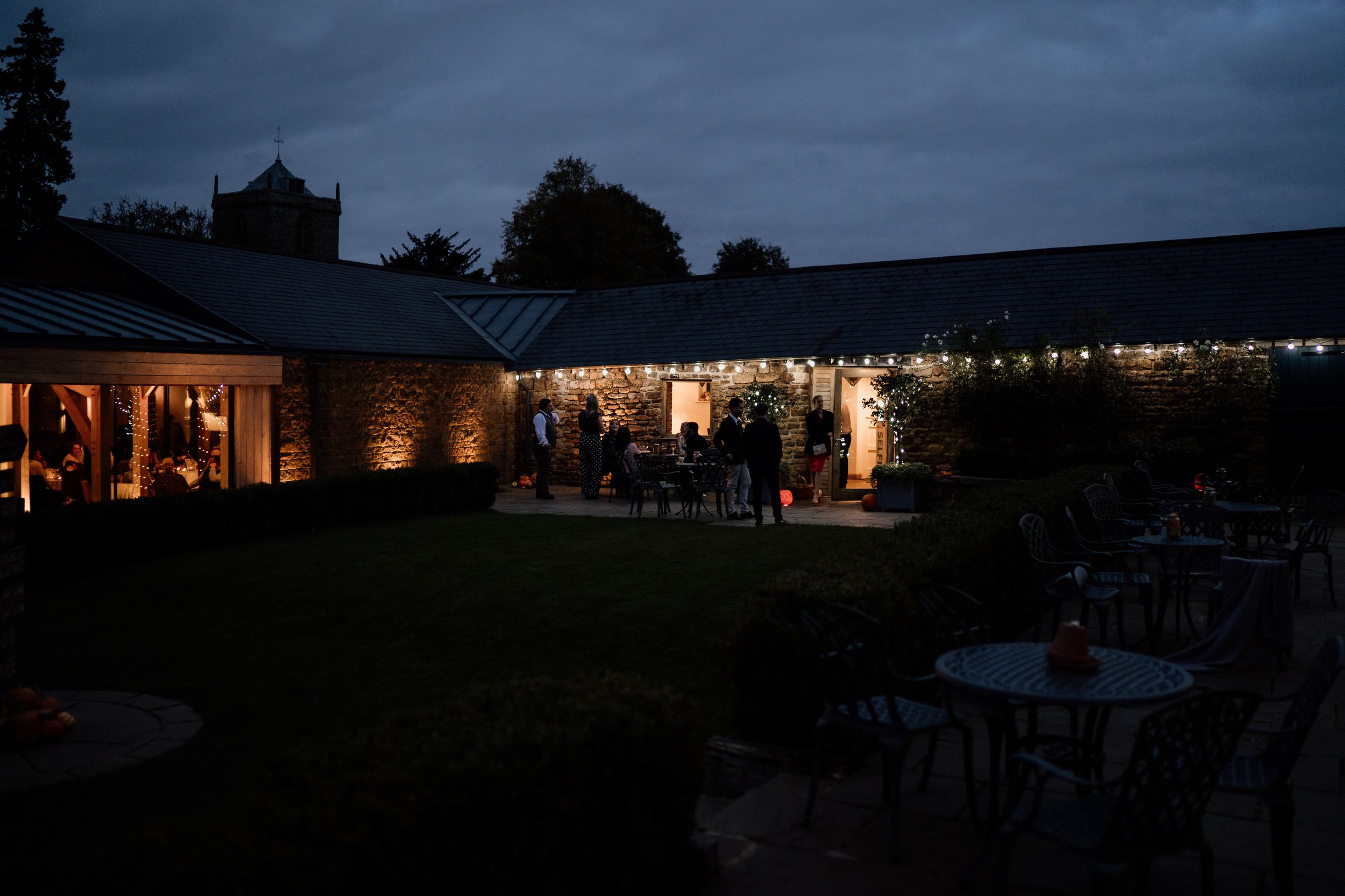 Evening wedding reception venue illuminated with string lights creating a romantic atmosphere of Dodford Manor Barns, Northamptonshire.