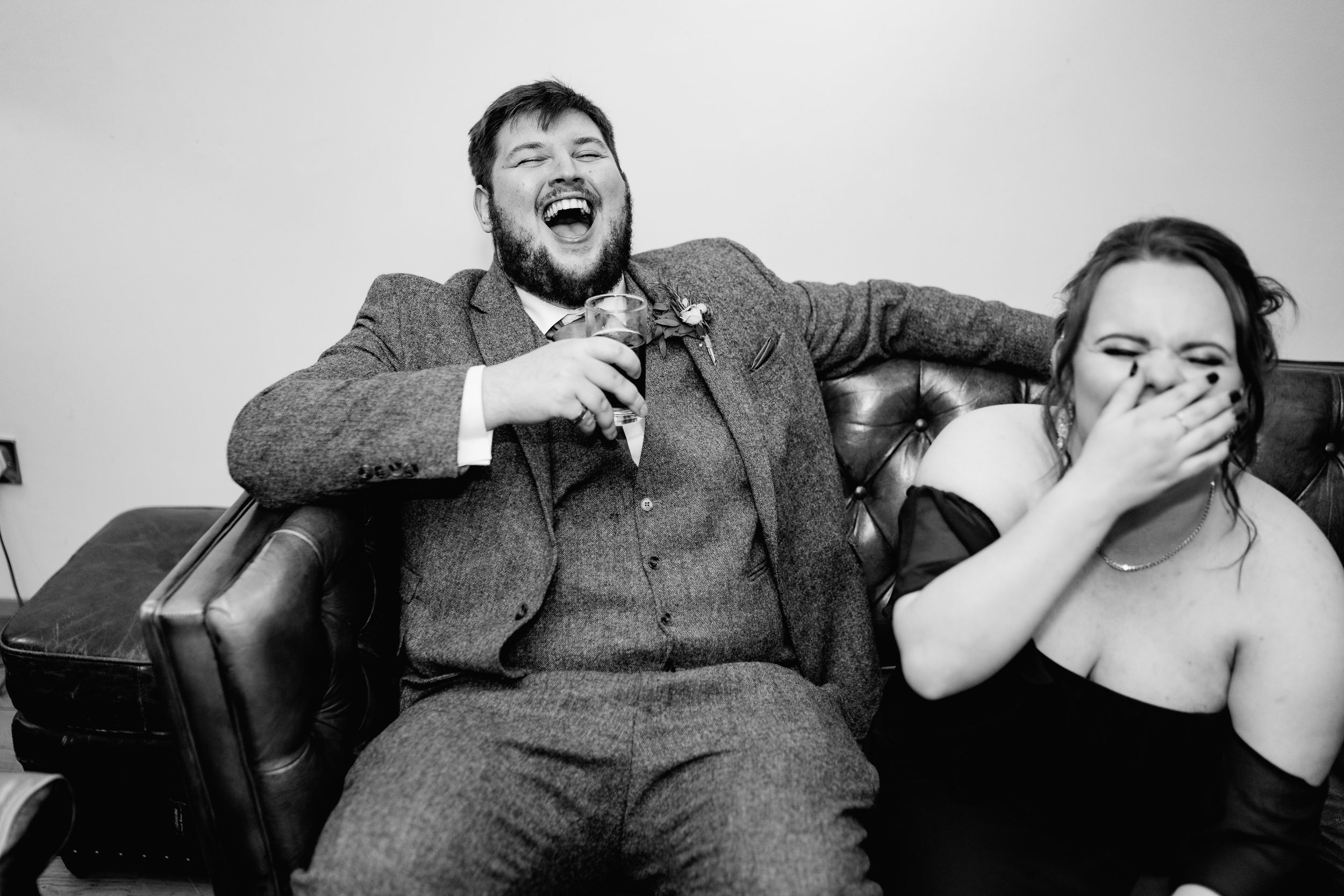 Black and white candid photo capturing laughter during wedding celebration.