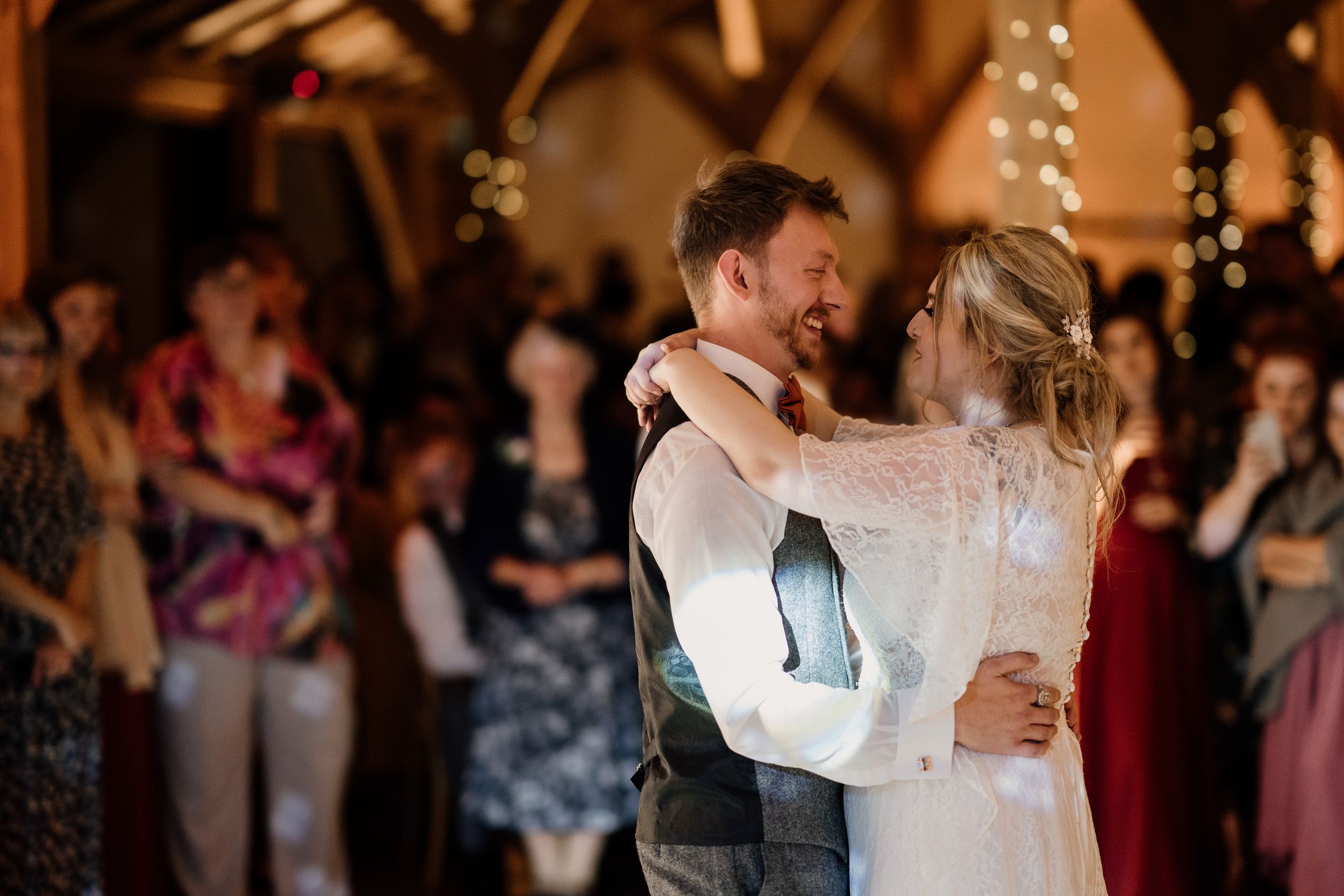 Couple shares romantic dance under twinkling lights at their wedding reception.