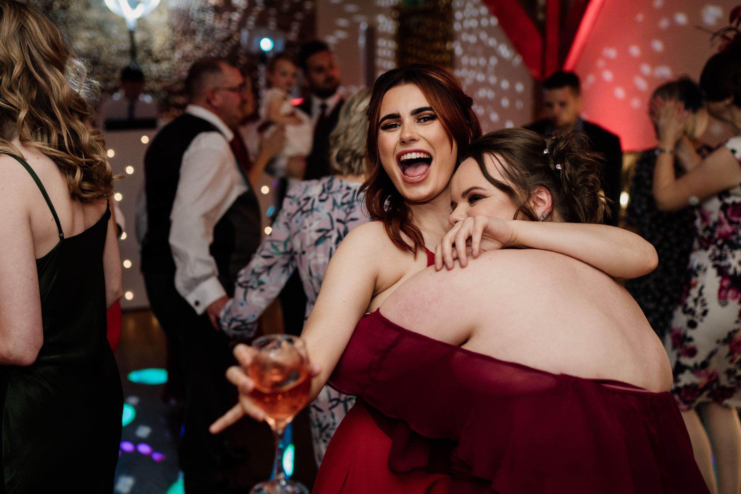Wedding guests dance and laugh together during a lively reception celebration.