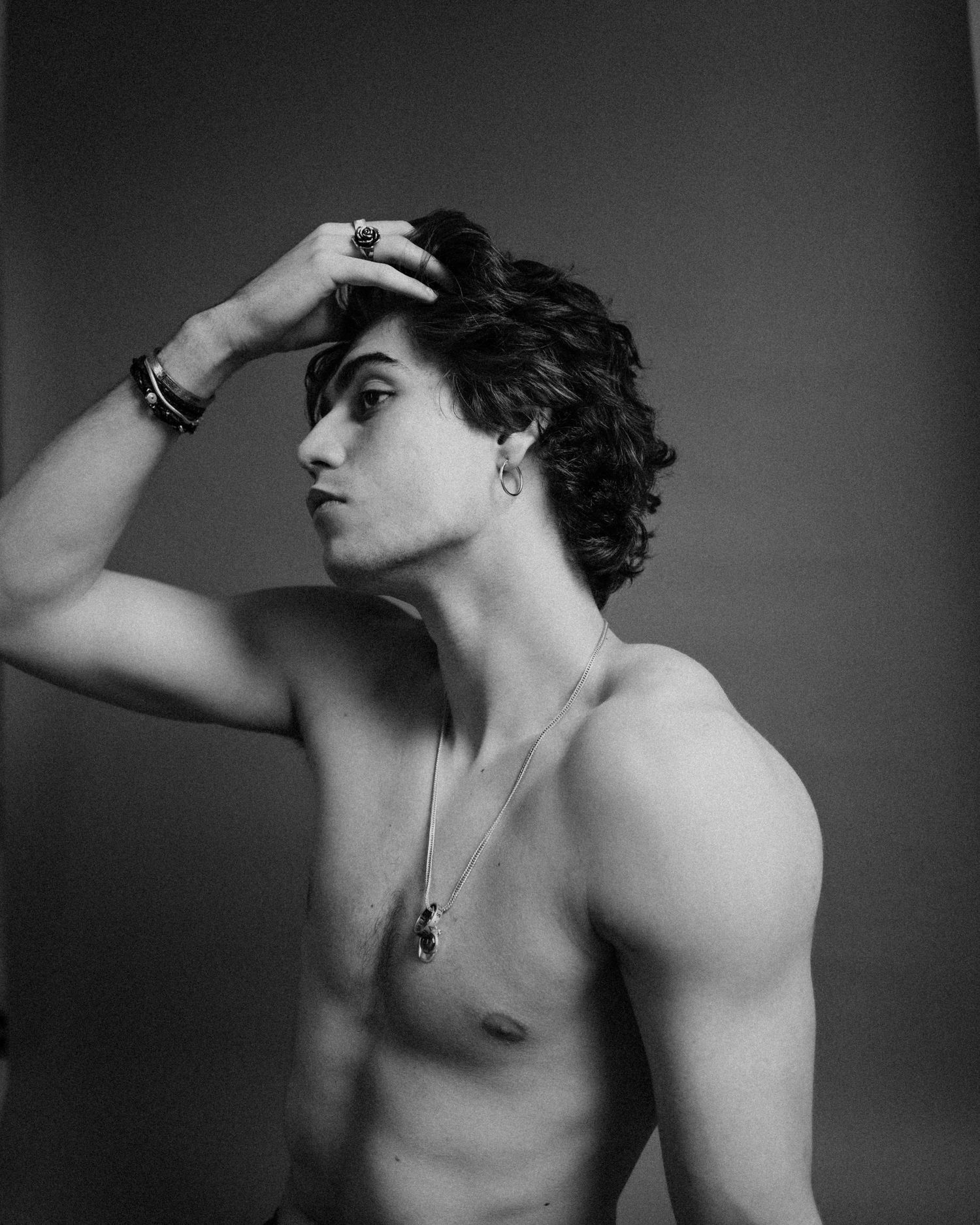 Artistic black and white studio portrait showing side profile pose highlighting dramatic lighting and curly hair.