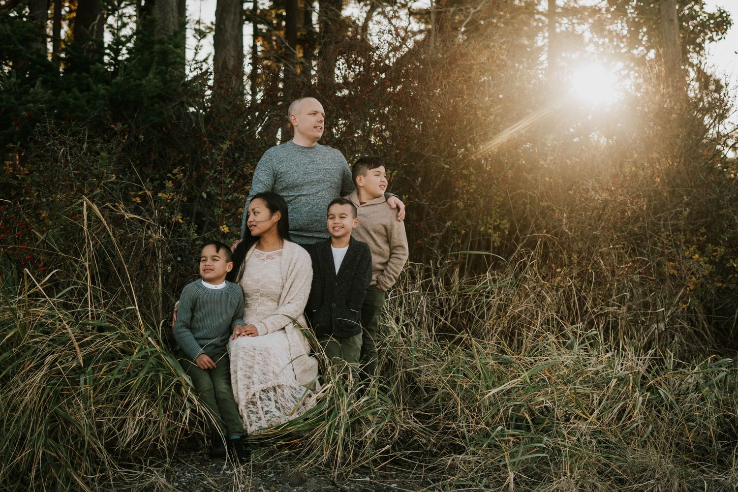 Beautiful portrait photography of family in Madrona Point beach grass on Vancouver Island during golden hour with sun beaming