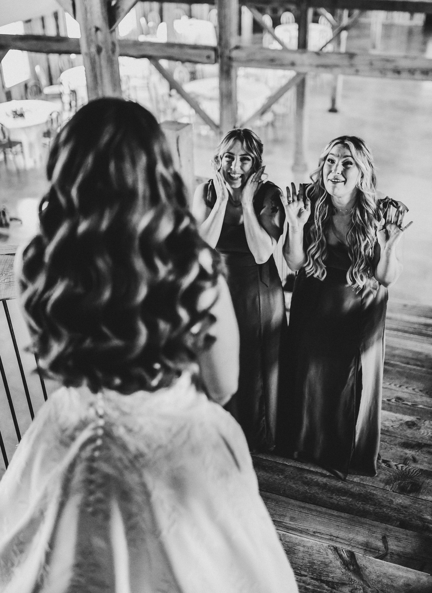 the bride stands on the rustic staircase as her matrons of honor see her for the first time