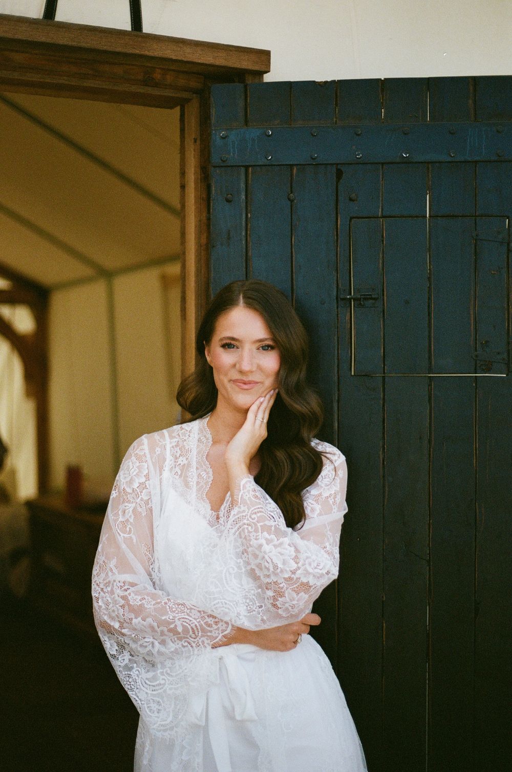 Bridal portrait in front of rustic blue door wearing lace long-sleeve wedding dress.