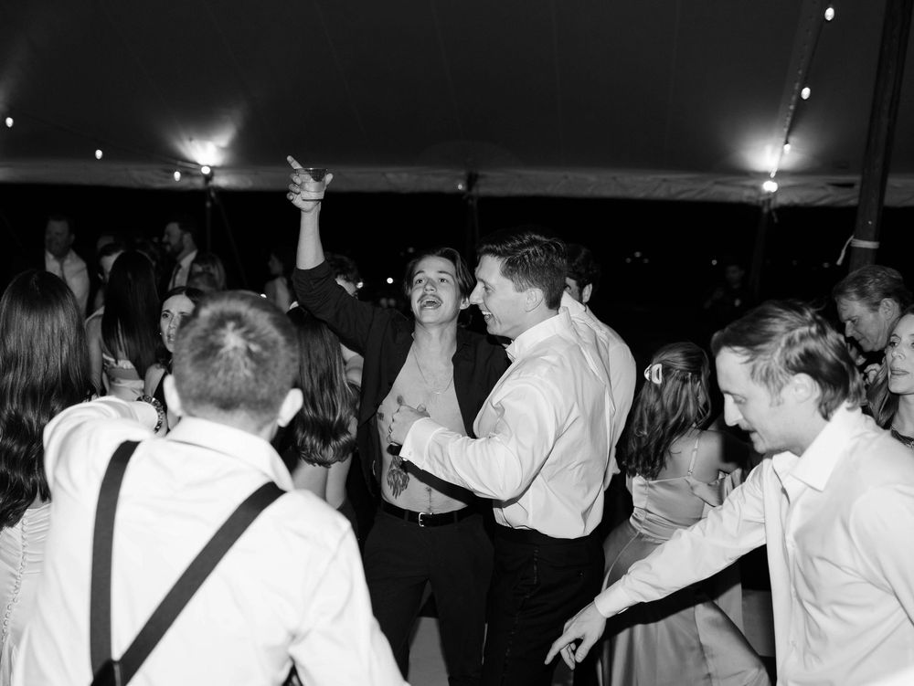Energetic dancing and celebration at a wedding reception under twinkling lights.