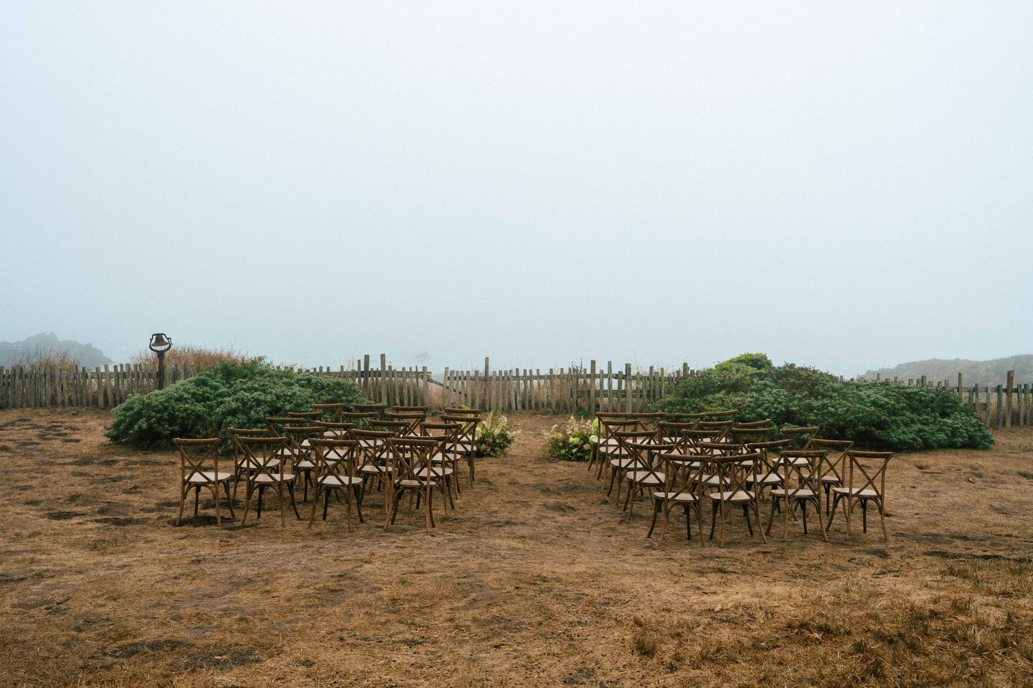 Outdoor wedding ceremony setup with wooden chairs arranged on a foggy bluff in the Sea Ranch Lodge's barn meadow.
