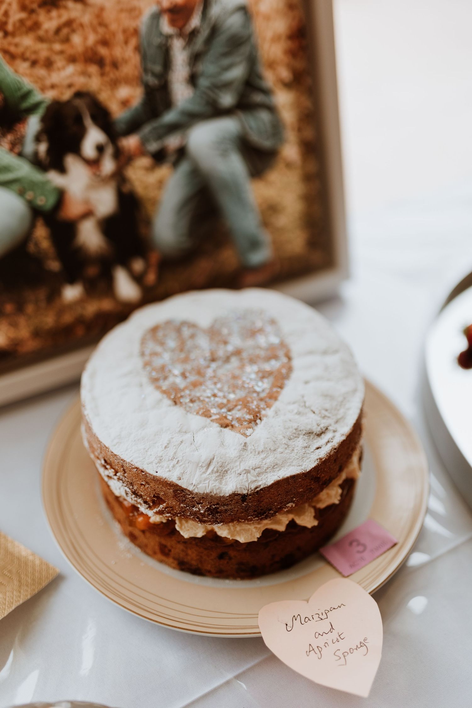 Three heart-shaped chocolate cakes dusted with powdered sugar displayed on beige plates with decorative name cards.