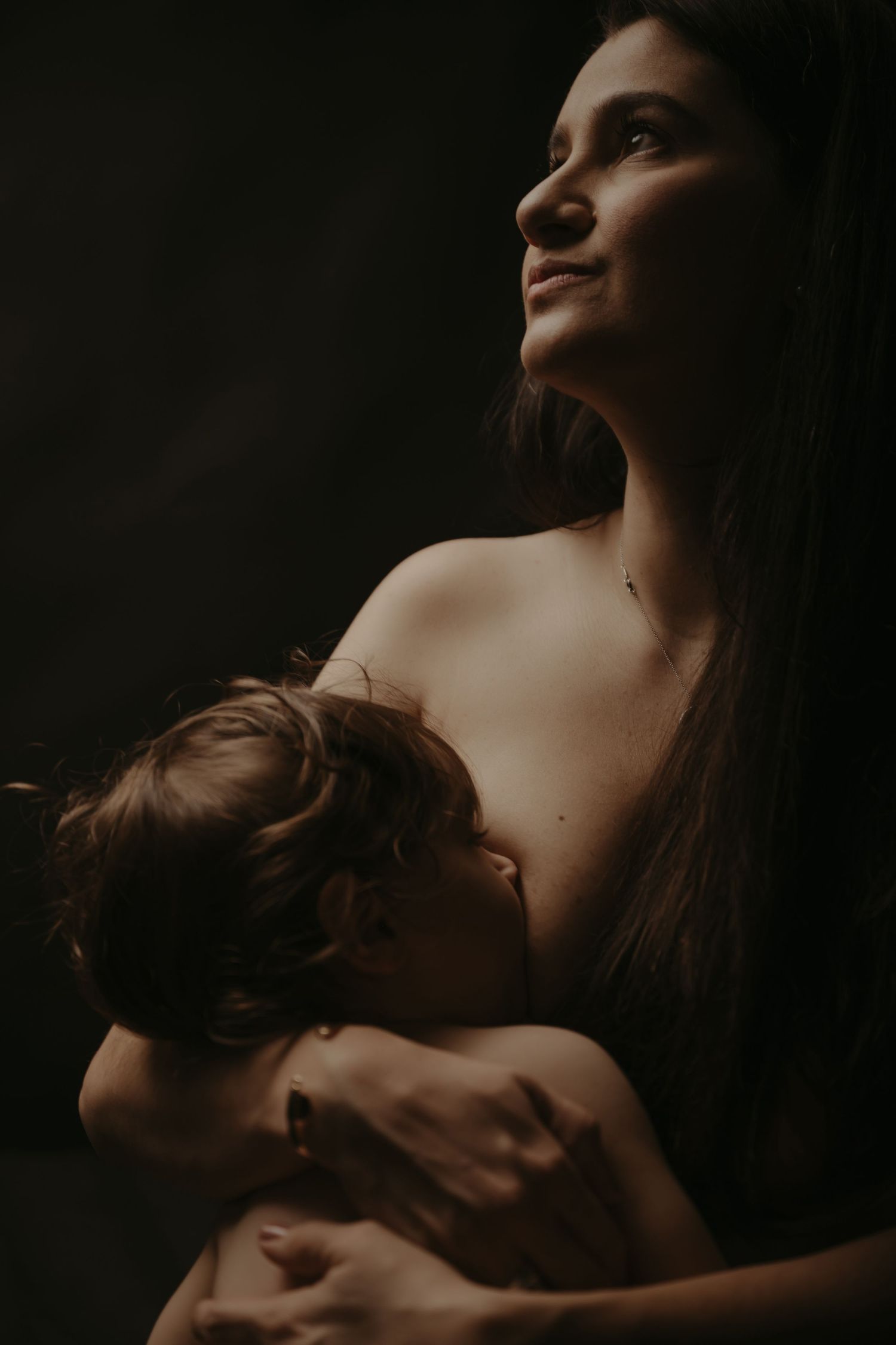 Moody and intimate portrait of mother and child bonding in dark atmospheric lighting.