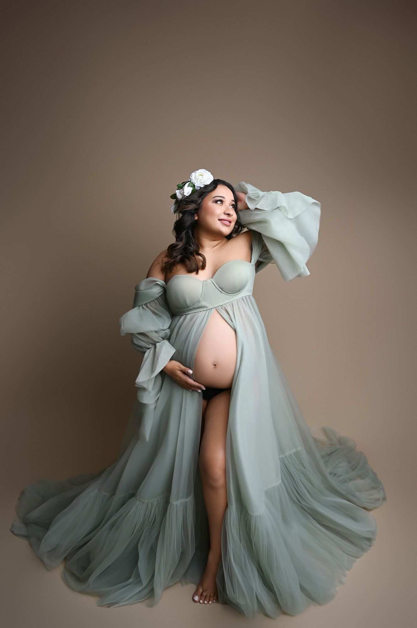 Elegant maternity photo of mom-to-be in green gown standing confidently in a Fresno fine art studio session.
