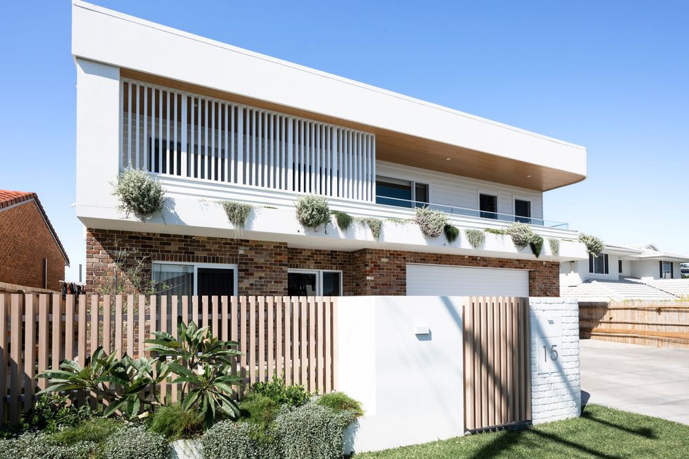 Modern residential building with clean white exterior walls, geometric lines, and vertical wood slat accents under blue sky.