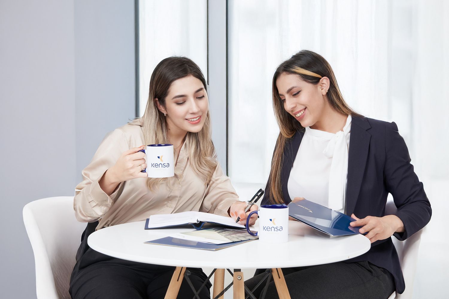 Dos personas viendo una página de carreras de una empresa en una hoja, que destaca sobre un currículum.