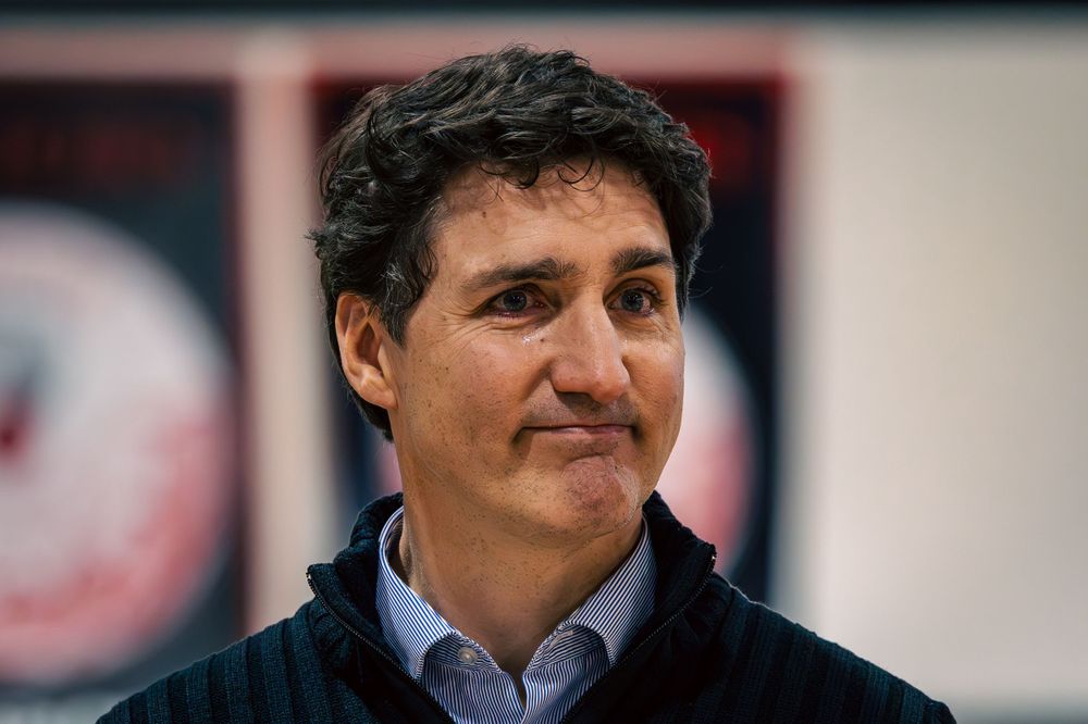 The Prime Minister of Canada smiles while standing in front of the Haida Nation.