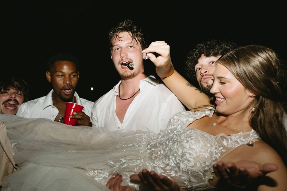Excited wedding guests celebrating and dancing during a nighttime reception.