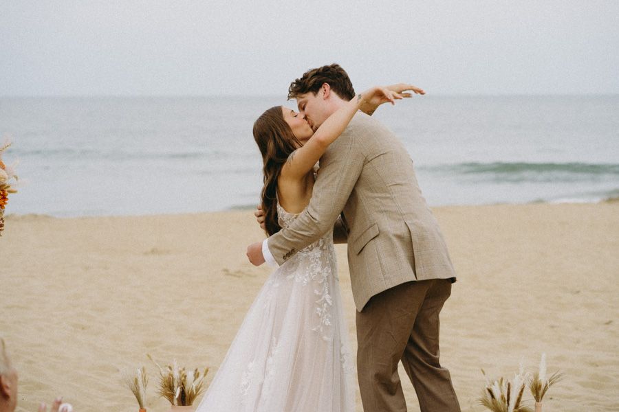 A romantic wedding moment captured on a beach with coastal decorations.