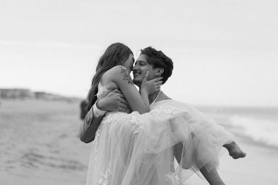 A romantic black and white photo of a couple embracing on the beach.