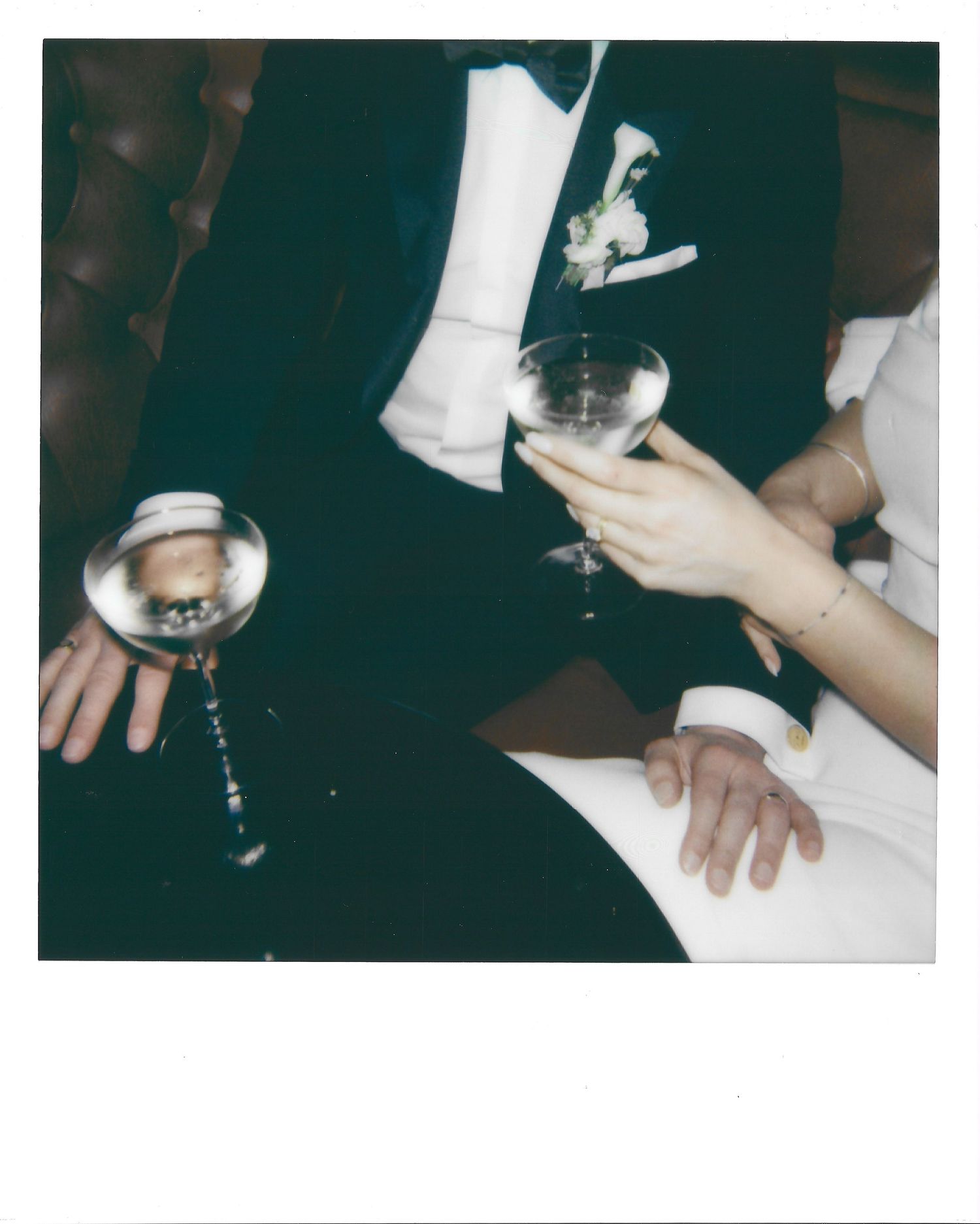 Hands holding wine glasses during a formal dinner celebration with white napkins and dark table decor.
