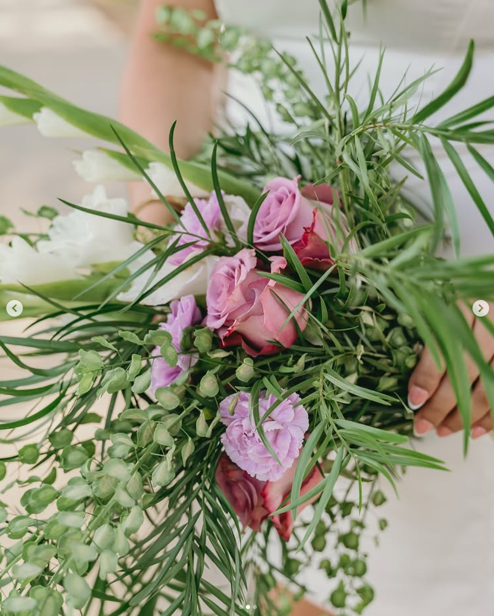 Close-up of a romantic floral arrangement with pink roses, green foliage and delicate filler flowers in soft natural light.
