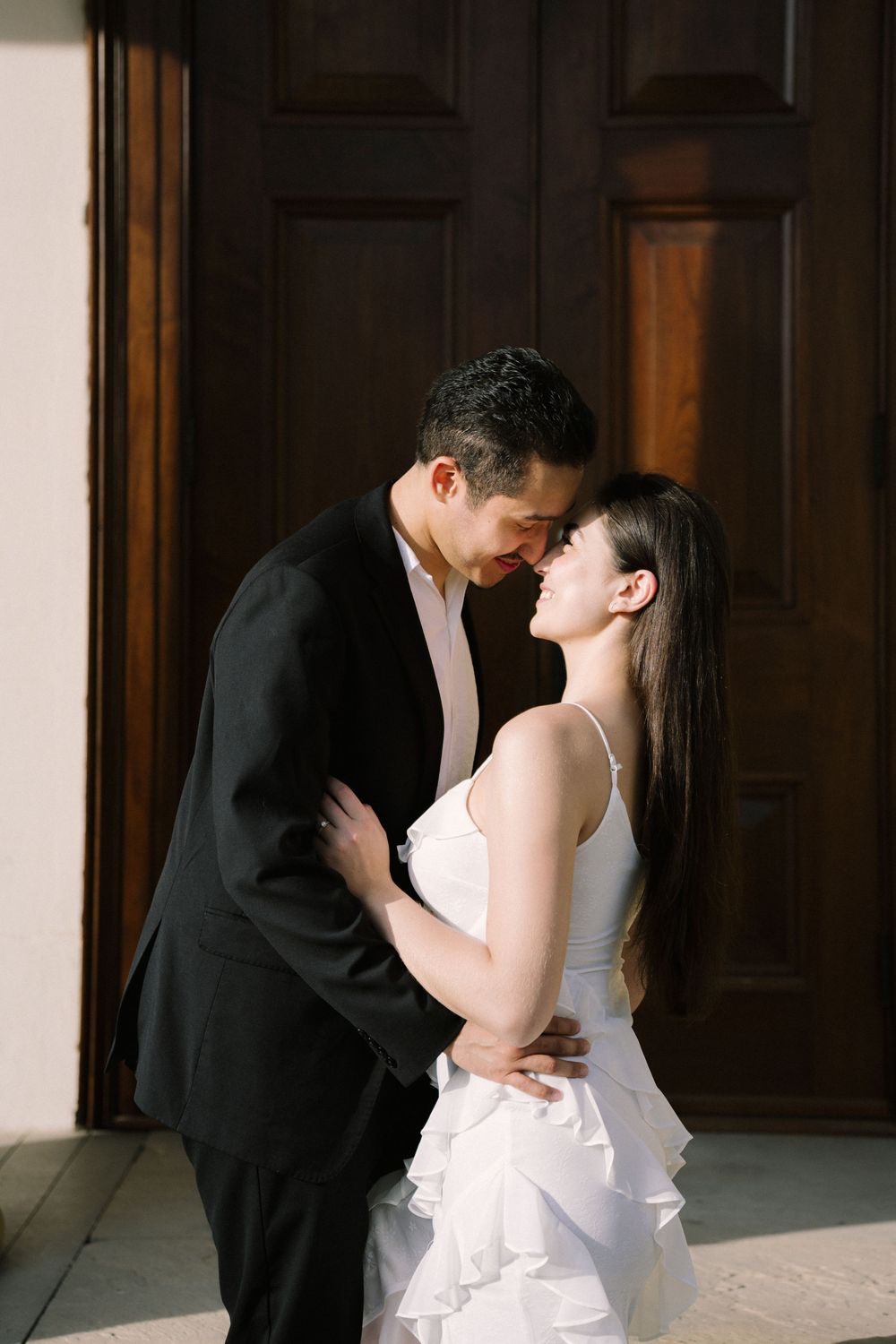 A couple in wedding attire sharing an intimate kiss in an indoor venue with wood paneling.