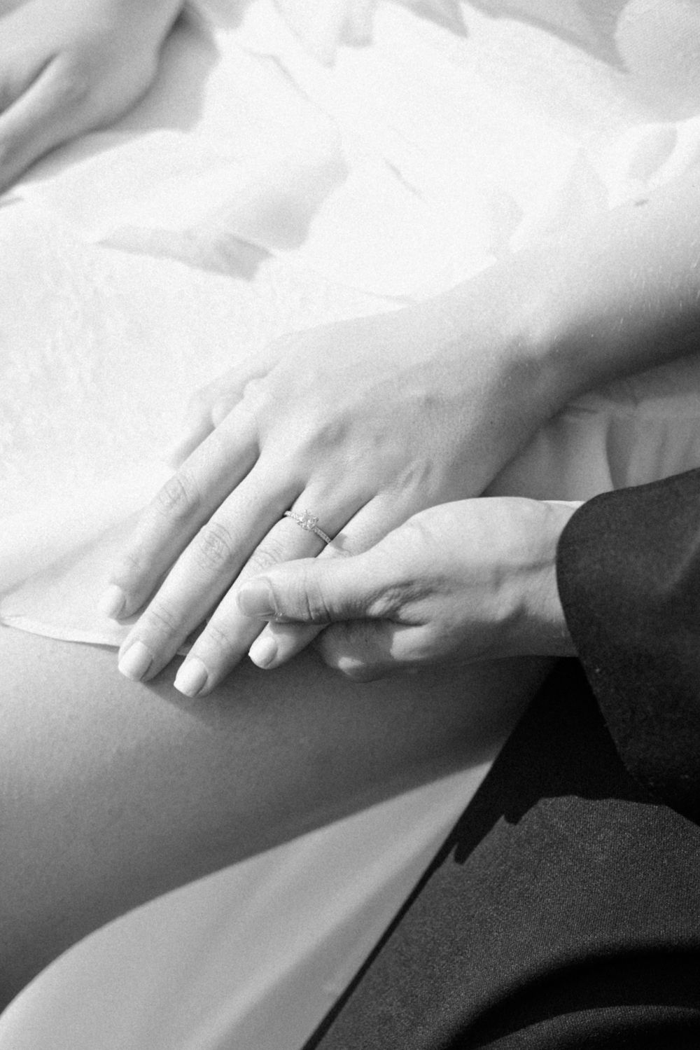 A black and white close-up photo of hands exchanging rings during a wedding ceremony.