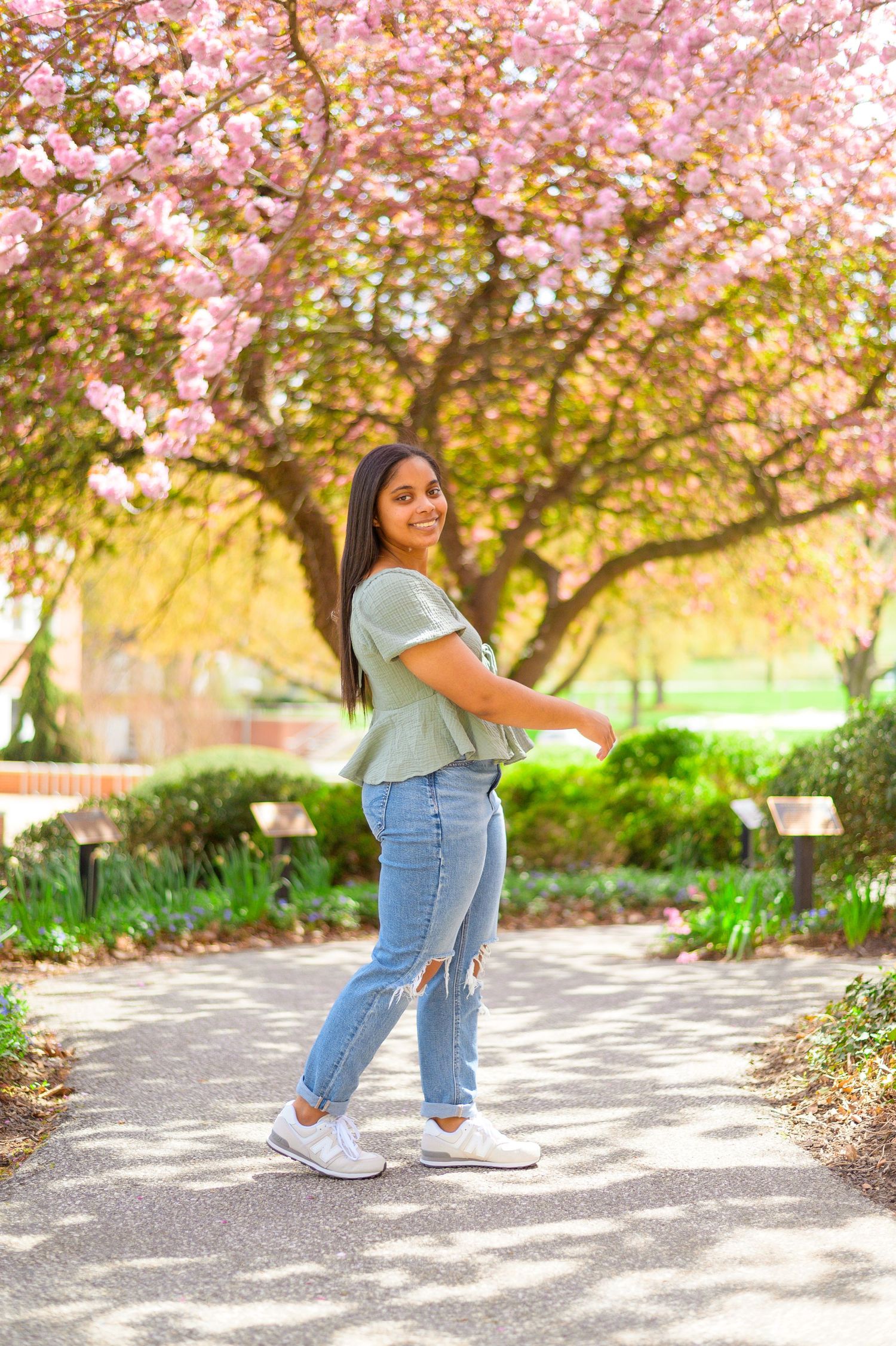 A casual spring portrait beneath a blossoming cherry tree in a park setting.
