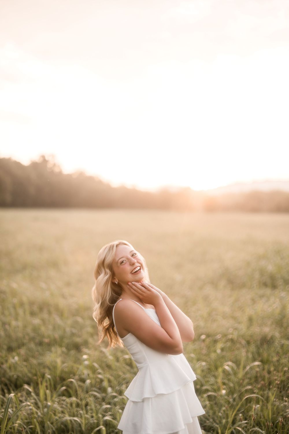 Person in white dress spins and laughs joyfully in a sunlit meadow at golden hour.
