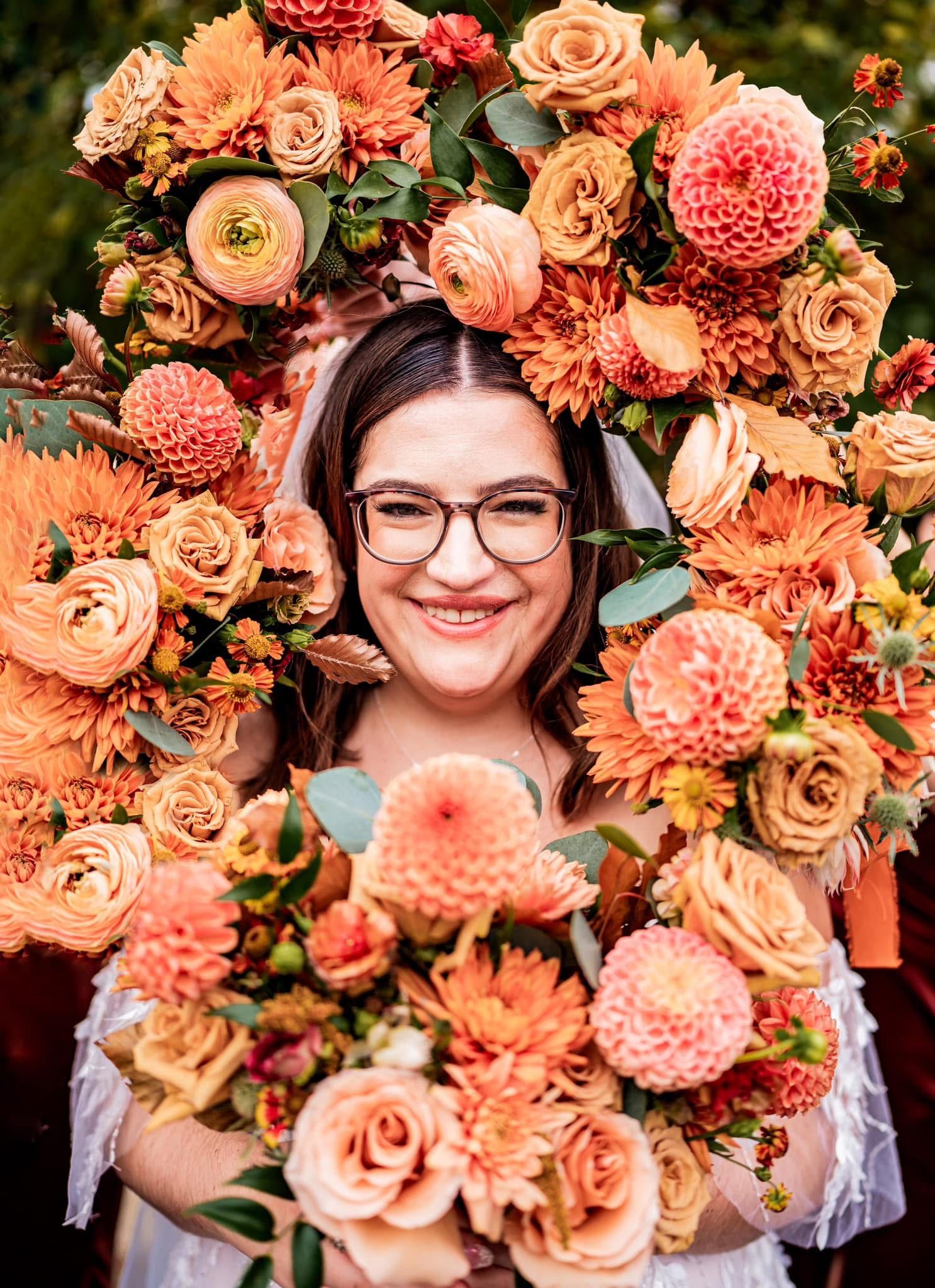 A stunning floral wreath made of peach roses, coral dahlias, and eucalyptus creates a beautiful circular frame.