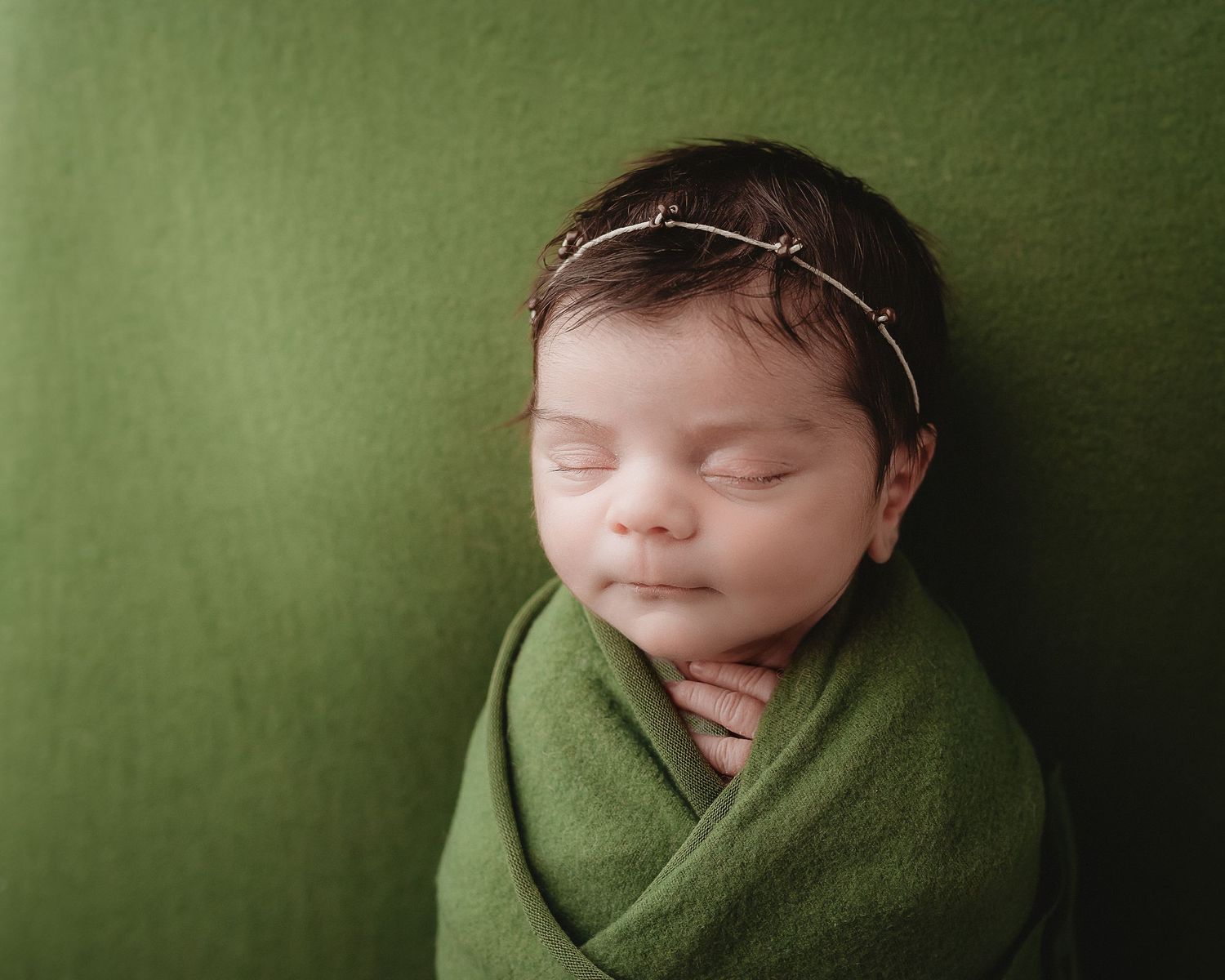 professional photo of a newborn baby wrapped in green