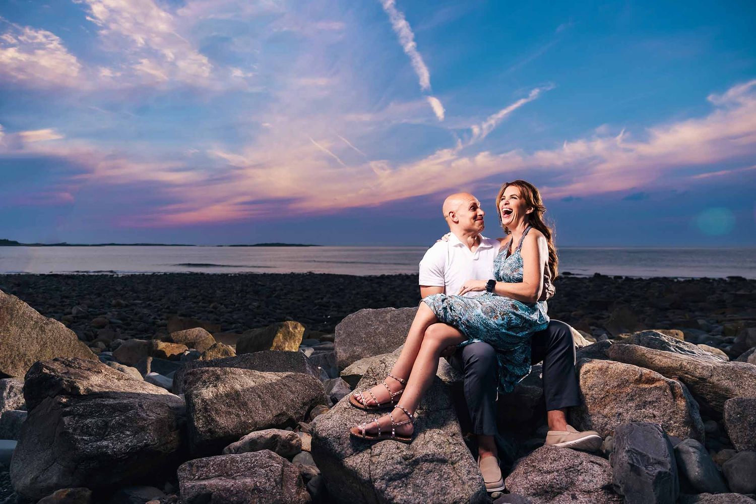 This groom shares a private joke with his fiancé that makes her burst out laughing during their sunset engagement session on Boston Harbor