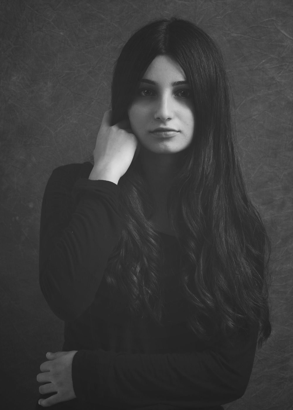 Black and white portrait of a woman with long dark hair wearing a black sweater in a moody artistic style.