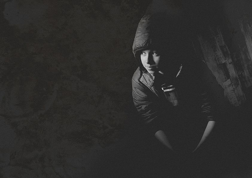Atmospheric noir style photo with subject in cap illuminated by dramatic lighting.