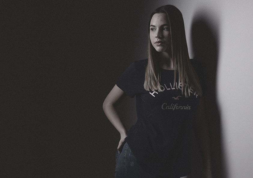 Moody portrait with dramatic shadow on plain background.