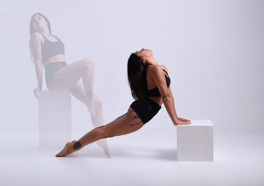 Artistic dance pose with figure on white cube creating dramatic silhouette effect.