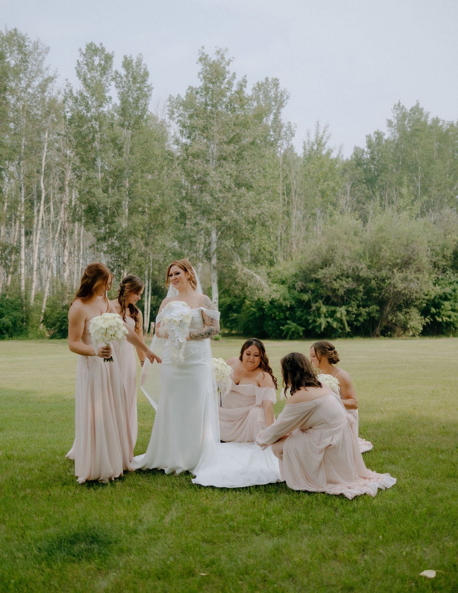 Wedding party gathered on grass with tall aspen trees in background.