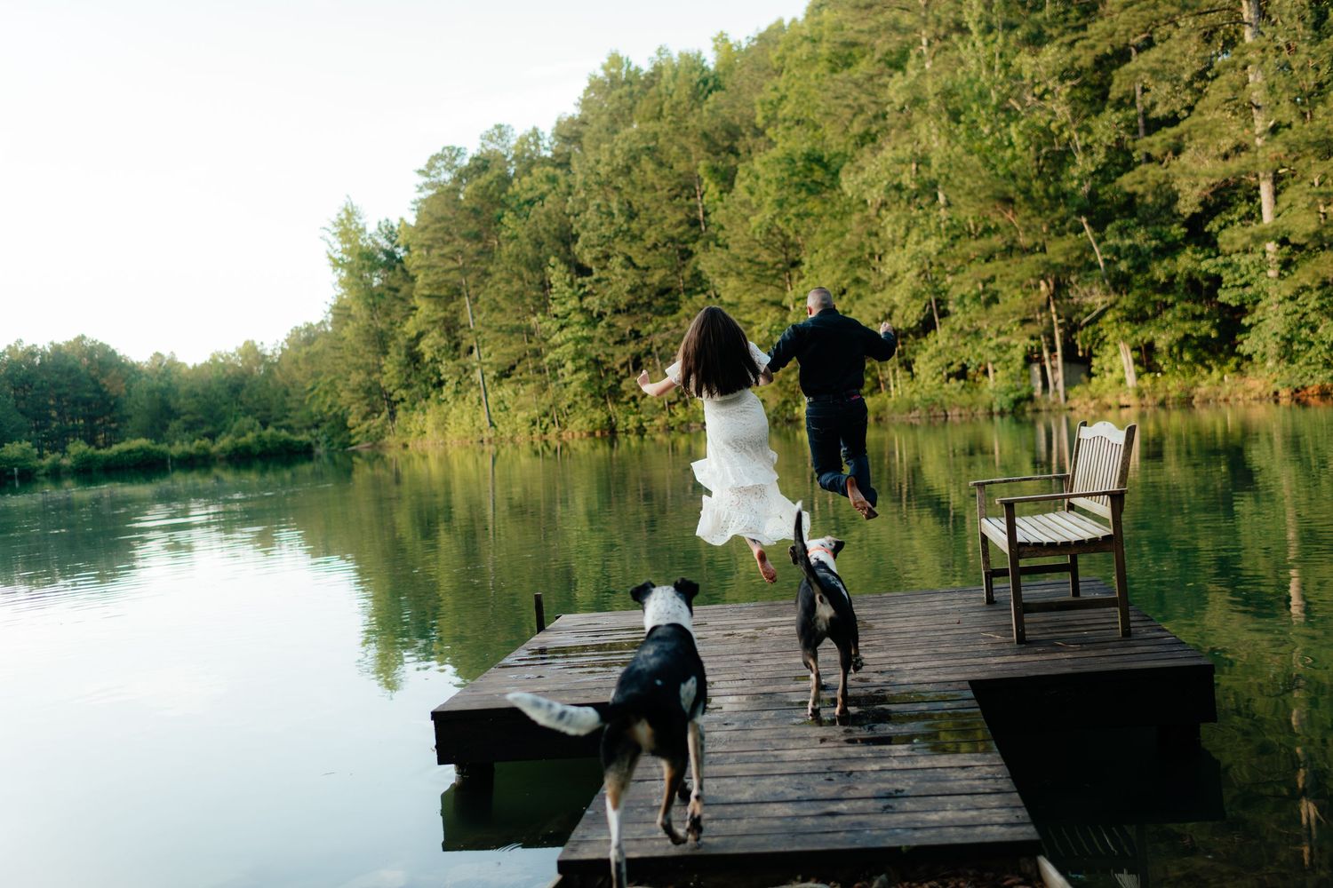 a couple kisses jumps off a dock into Henry Neely Lake during their engagement photos in Gadsden, Alabama