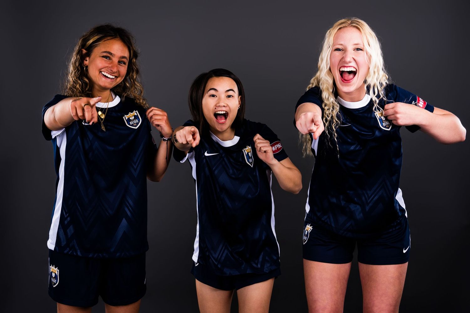 Three team members from the WPSL Reign FC II team are posing for the camera during a team media day.