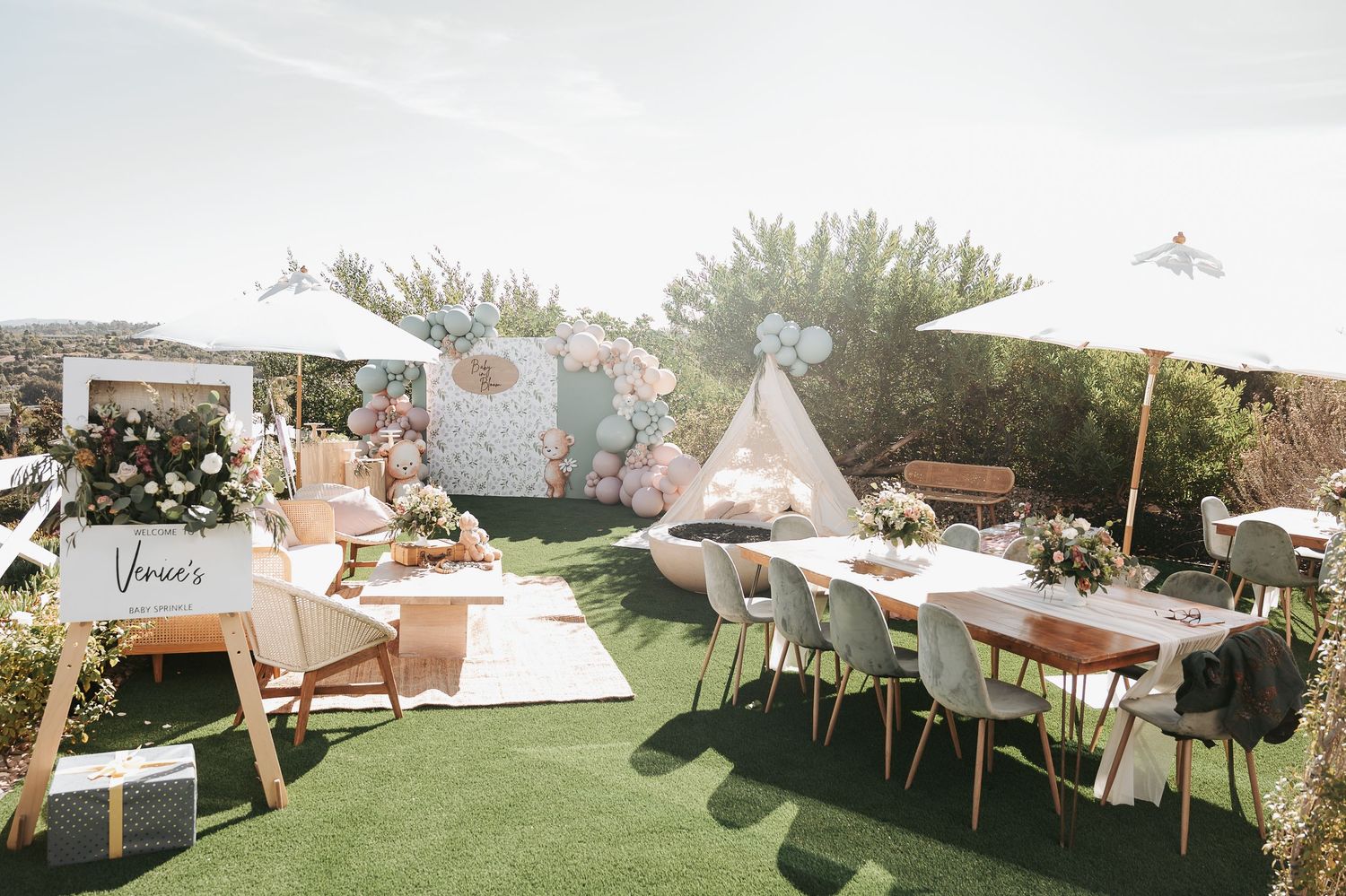 Outdoor event setup with teepee, tables and chairs on artificial grass under a sunny sky.