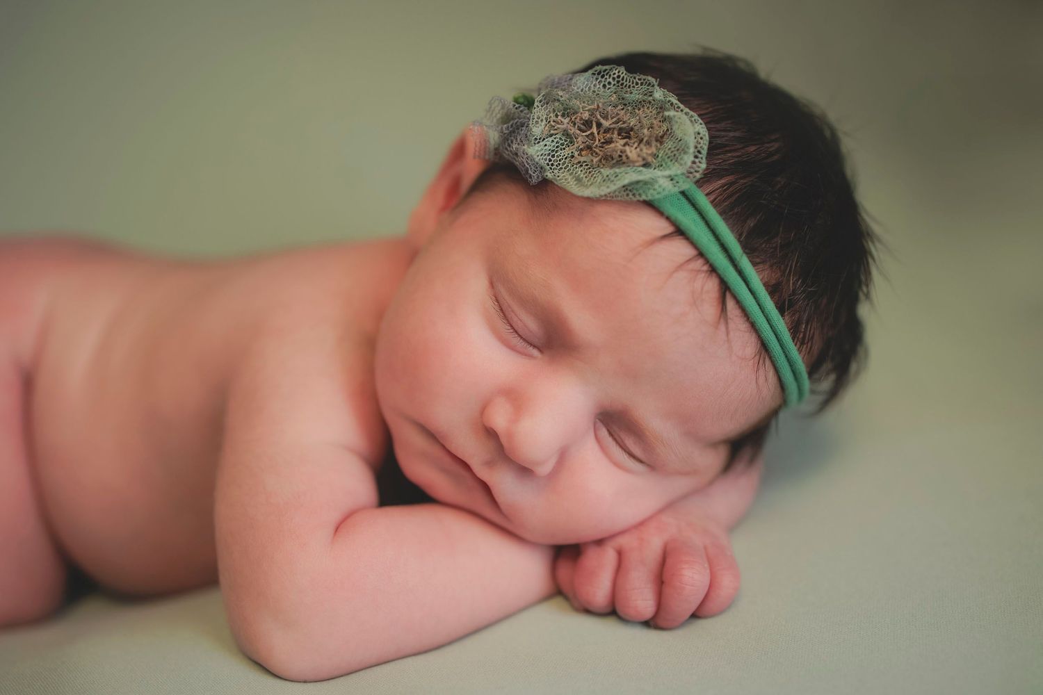 Sleeping newborn baby wearing green lace headband. Newborn photographer in Gosport Hampshire, Newborn photo studio, baby photos