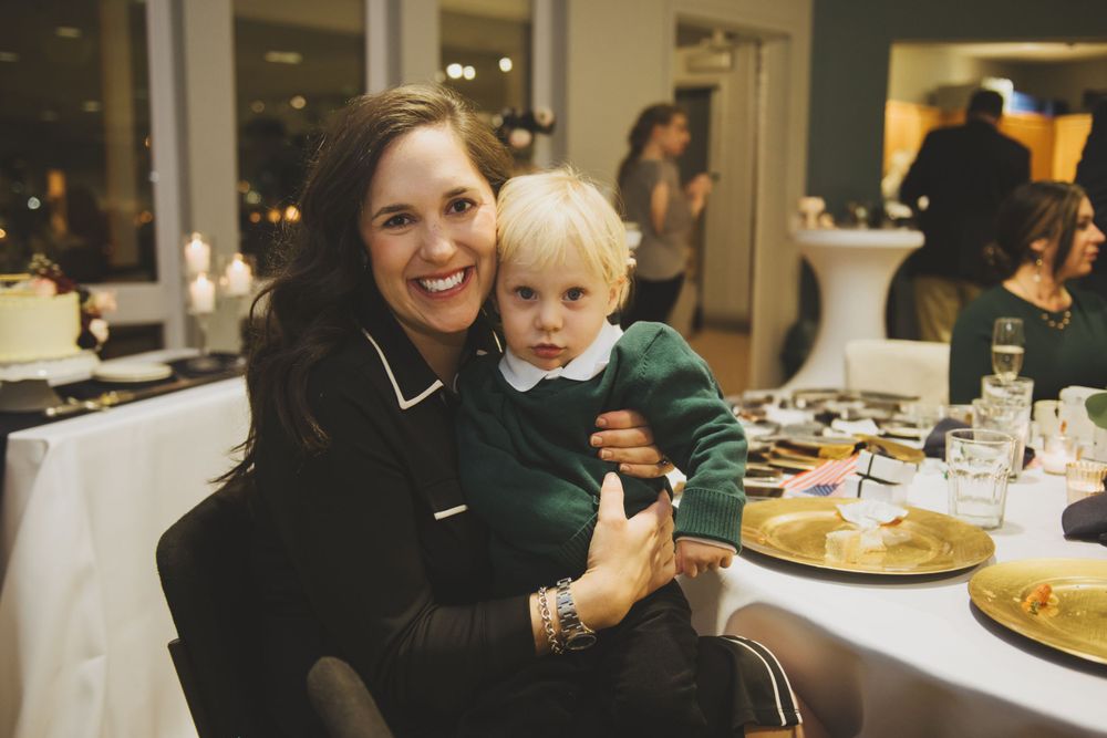 Mother and toddler enjoying quality time together at a reception dinner table filled with plates of food.
