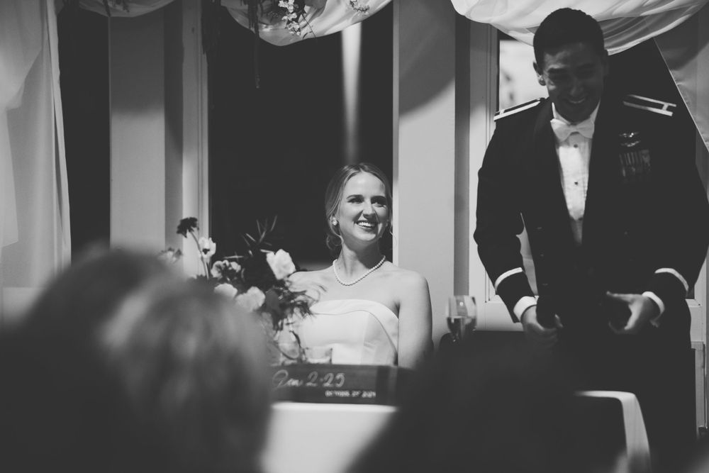 Black and white photo of a bride and groom laughing during a wedding reception celebration.