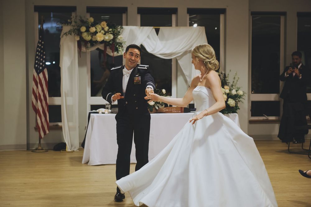 A couple shares a special dance moment during their wedding reception on a wooden dance floor beside an American flag.