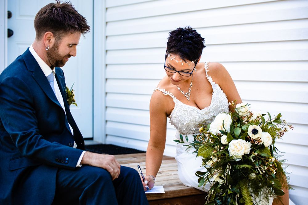 A couple shares a quiet moment on white wooden steps during their wedding celebration.