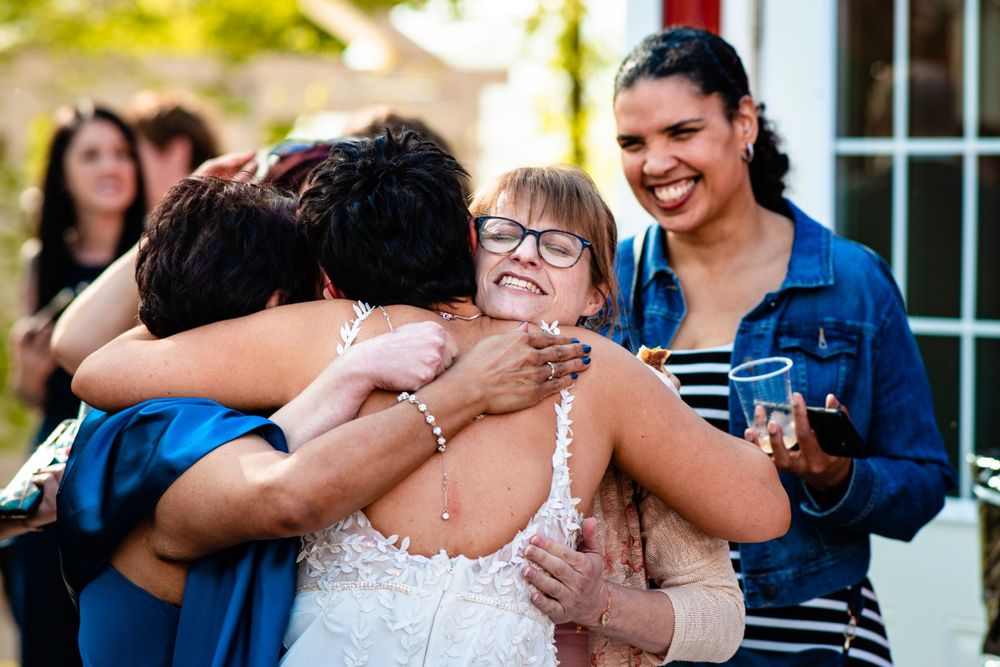 Emotional group hug shared during outdoor wedding celebration with natural garden backdrop.