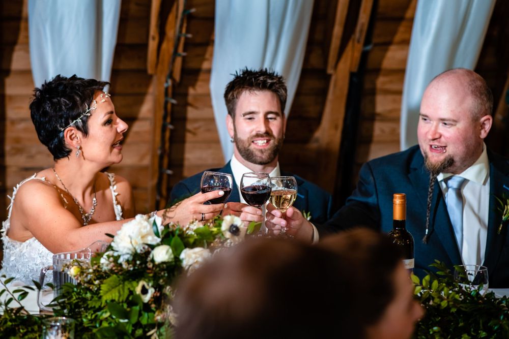 Wedding reception guests toasting and laughing during dinner speeches at an elegant venue.
