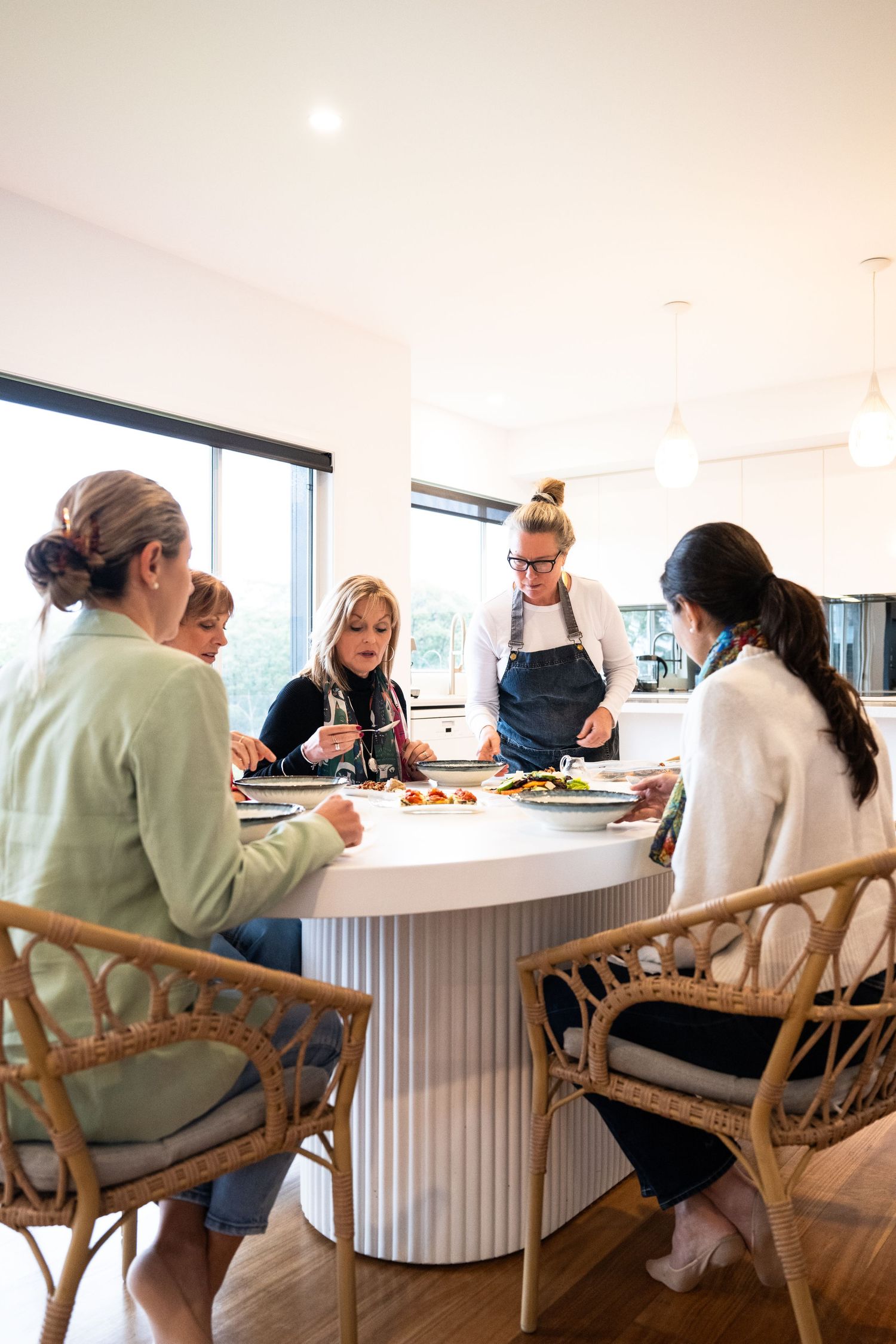A group gathered around a modern white circular table for a casual dining experience indoors.