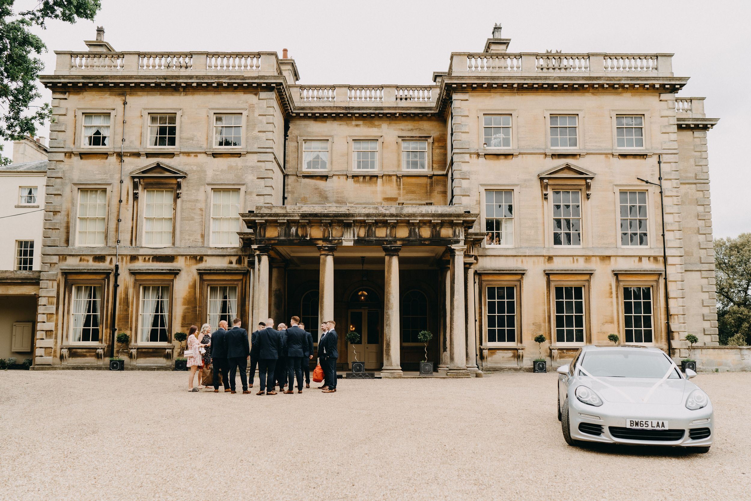Prestwold Hall elegant stone manor house with classic Georgian architecture and a silver sports car parked outside the entrance.