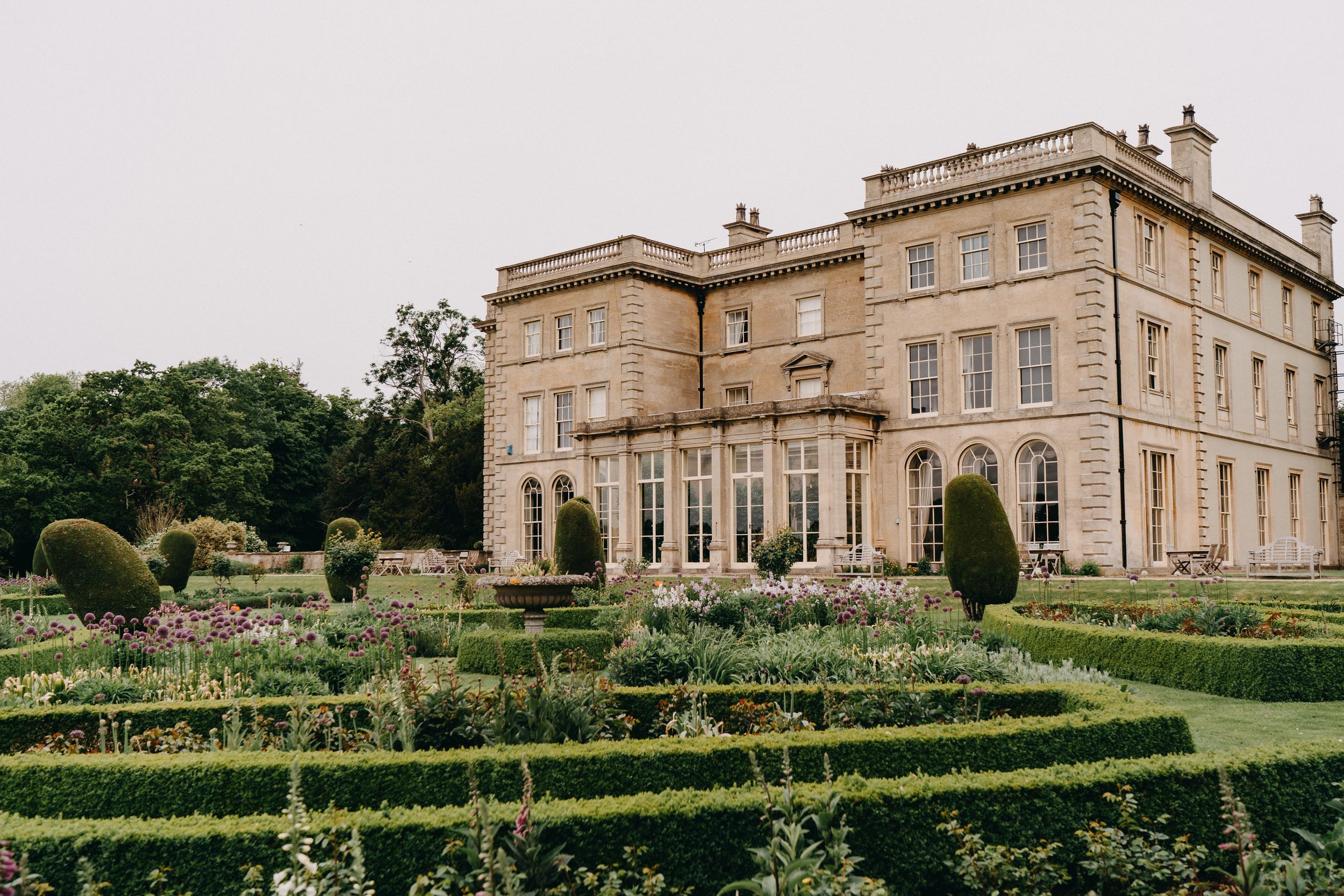 Elegant stone mansion of Prestwold Hall with manicured topiary garden maze and symmetrical landscaping in traditional English style.