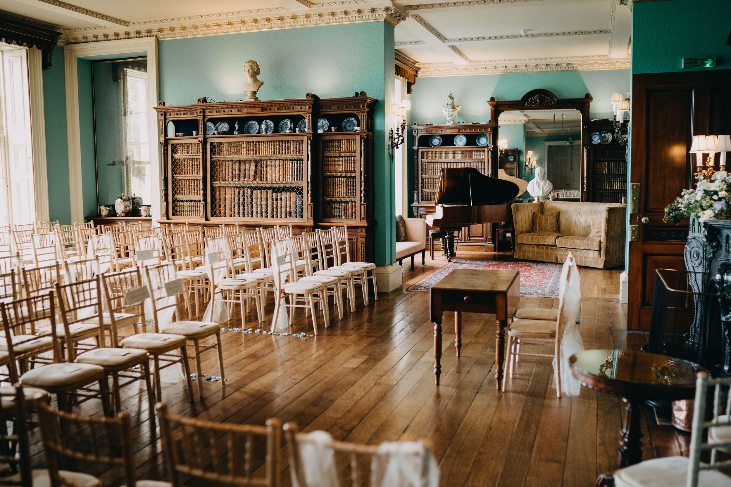 Vintage ceremony aroomt Prestwold Hall with wooden floors, chiavari chairs, and built-in bookshelves arranged for an intimate event space.