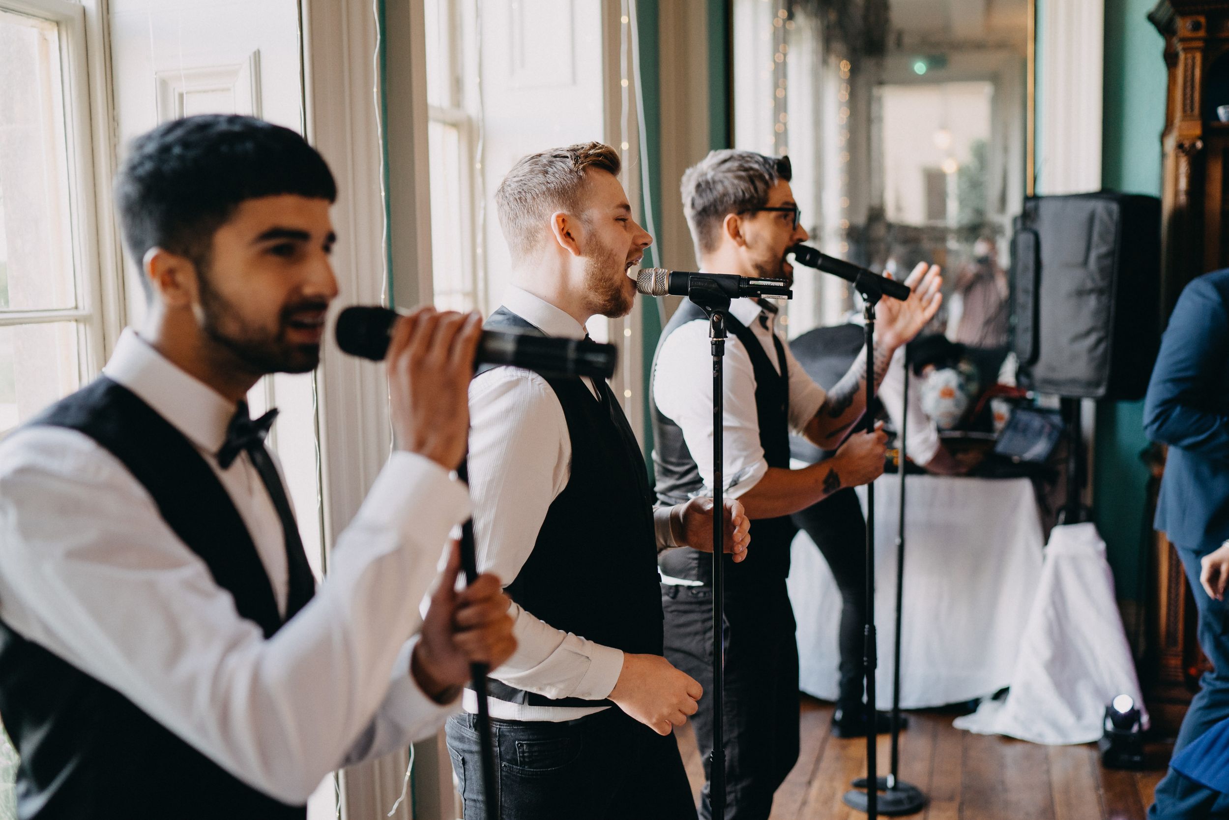 A live band performs at an elegant event, with musicians in formal attire playing instruments and singing into microphones.